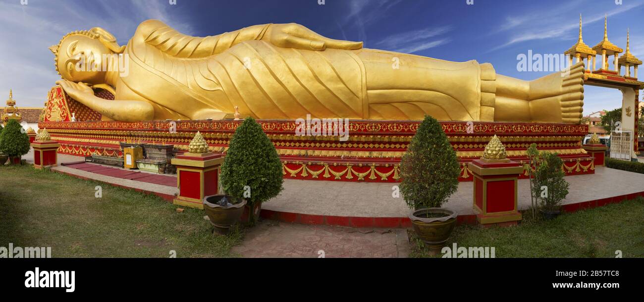Wide Panoramic View of Reclining Gold Covered Buddha Statue or the Great Stupa, a sacred Buddhist Monument in Pha That Luang, Vientiane, Laos Capital Stock Photo
