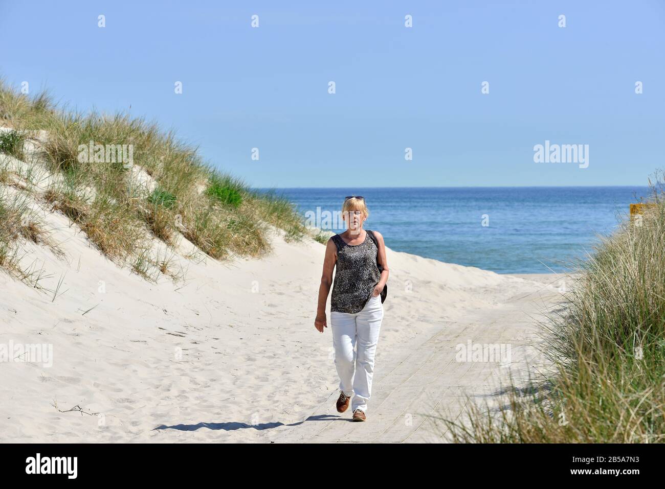 A woman walking to beach with the sea in background, Sandhammaren, Ystad, Skane, Sweden Stock Photo