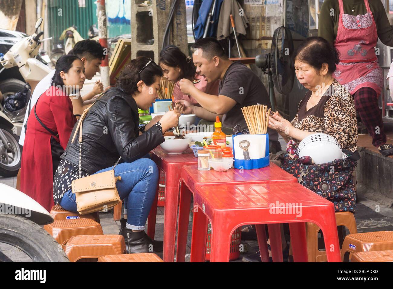 Hanoi street food People having lunch on plastic stools in the Old
