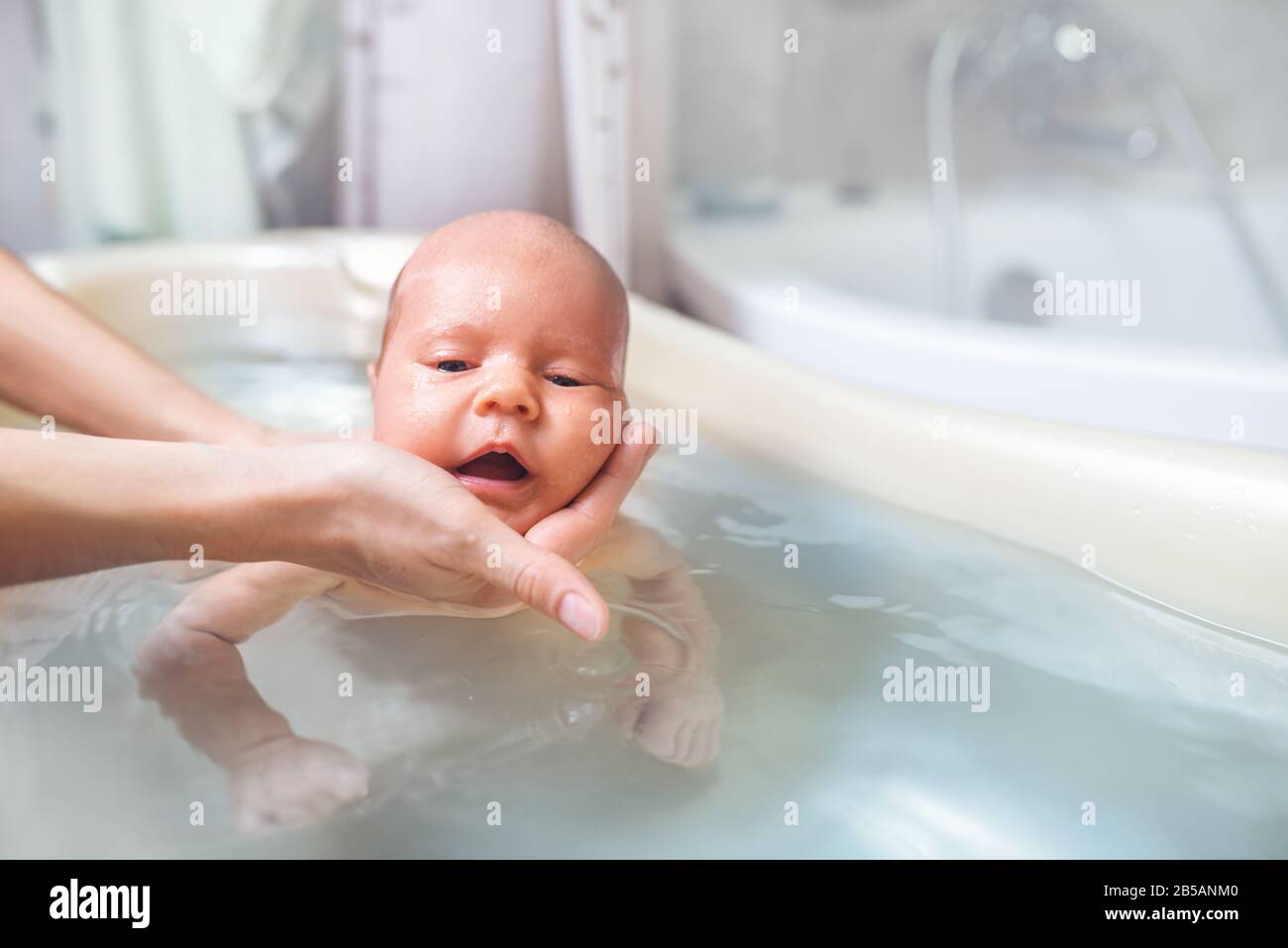 kan niet zien modder Reizende handelaar Small cute big-eyed beautiful baby bathes in warm water in the hands of a  caring mother. The concept of baby care and child care Stock Photo - Alamy