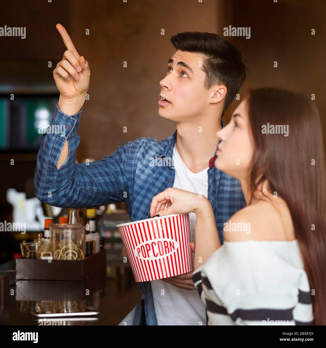 Millennial man with his girlfriend buying popcorn in cinema cafeteria