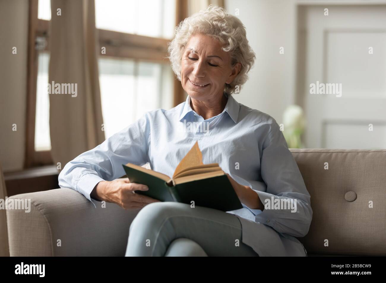 Mature woman relax at home reading paper book Stock Photo