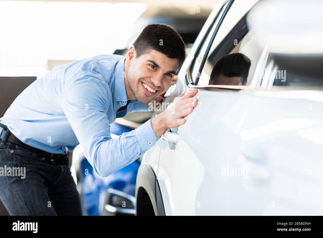Happy Guy Touching His Auto In Dealership Showroom Stock Photo Alamy