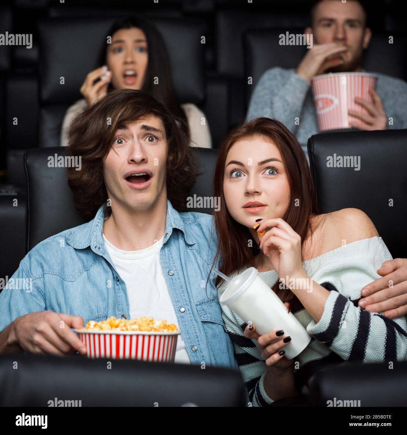 Leisure activity. Emotional young man with his girlfriend watching thriller in movie theater Stock Photo