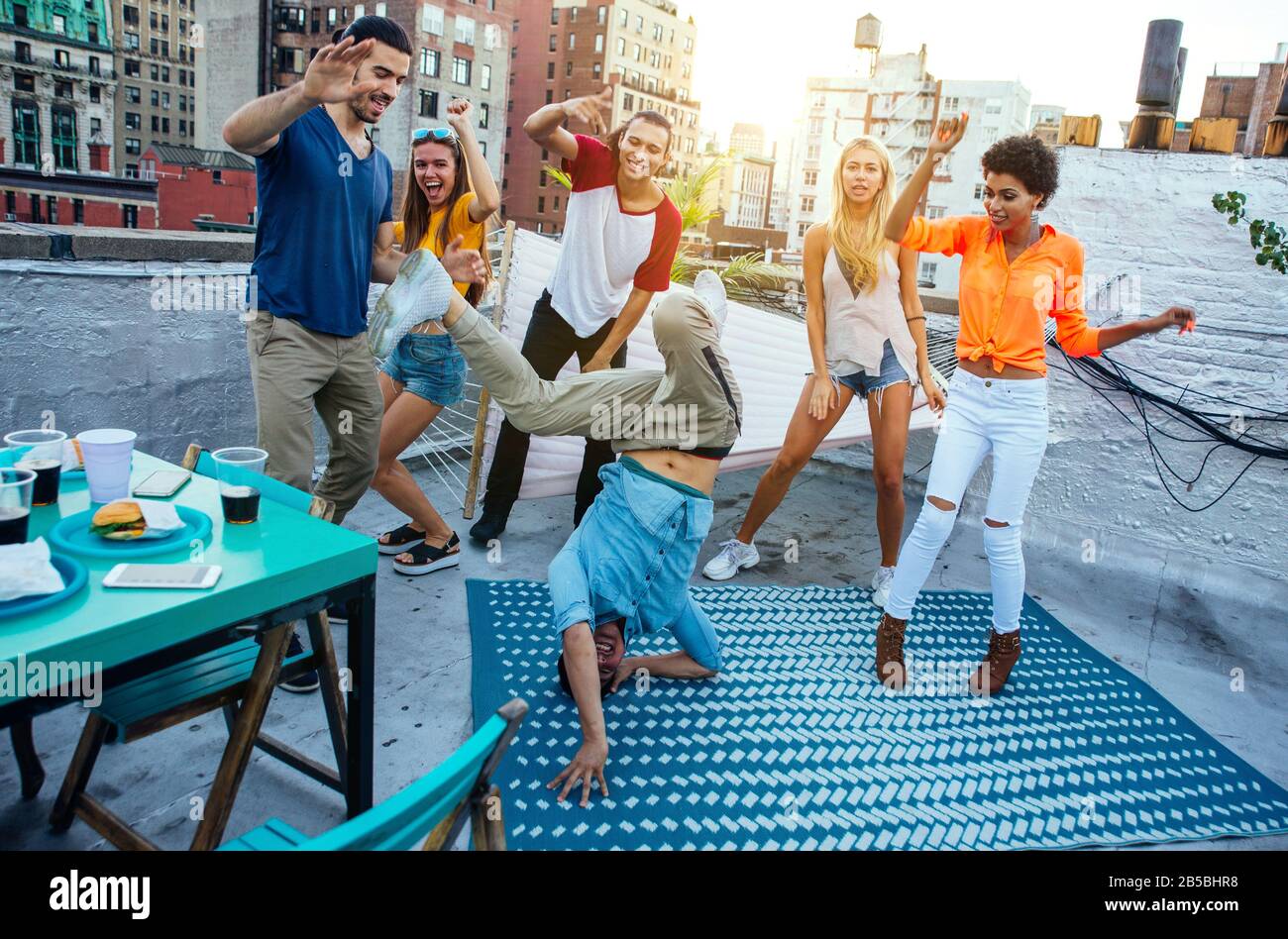 Group of friends spending time together on a rooftop in New york city, lifestyle concept with happy people Stock Photo