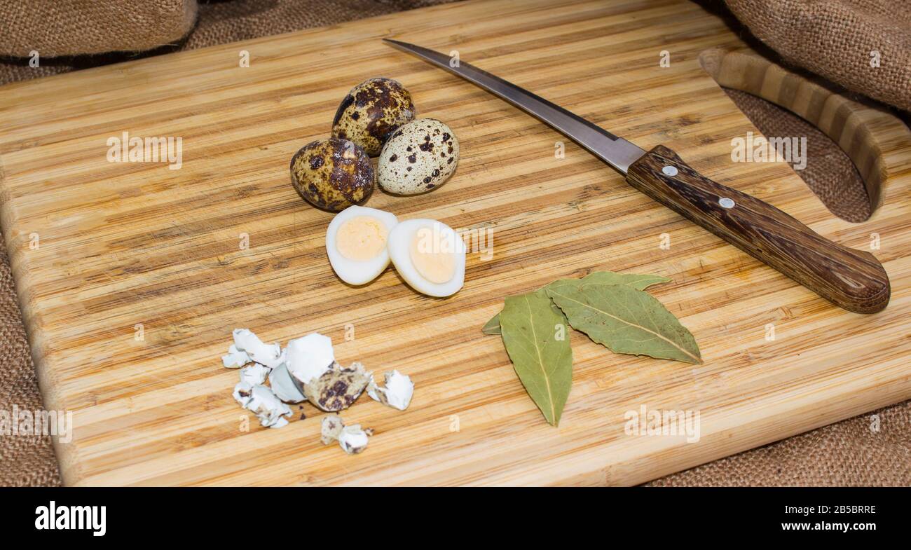 Hard boiled quail egg halves with egg shells on wooden board, photographed with natural light Stock Photo