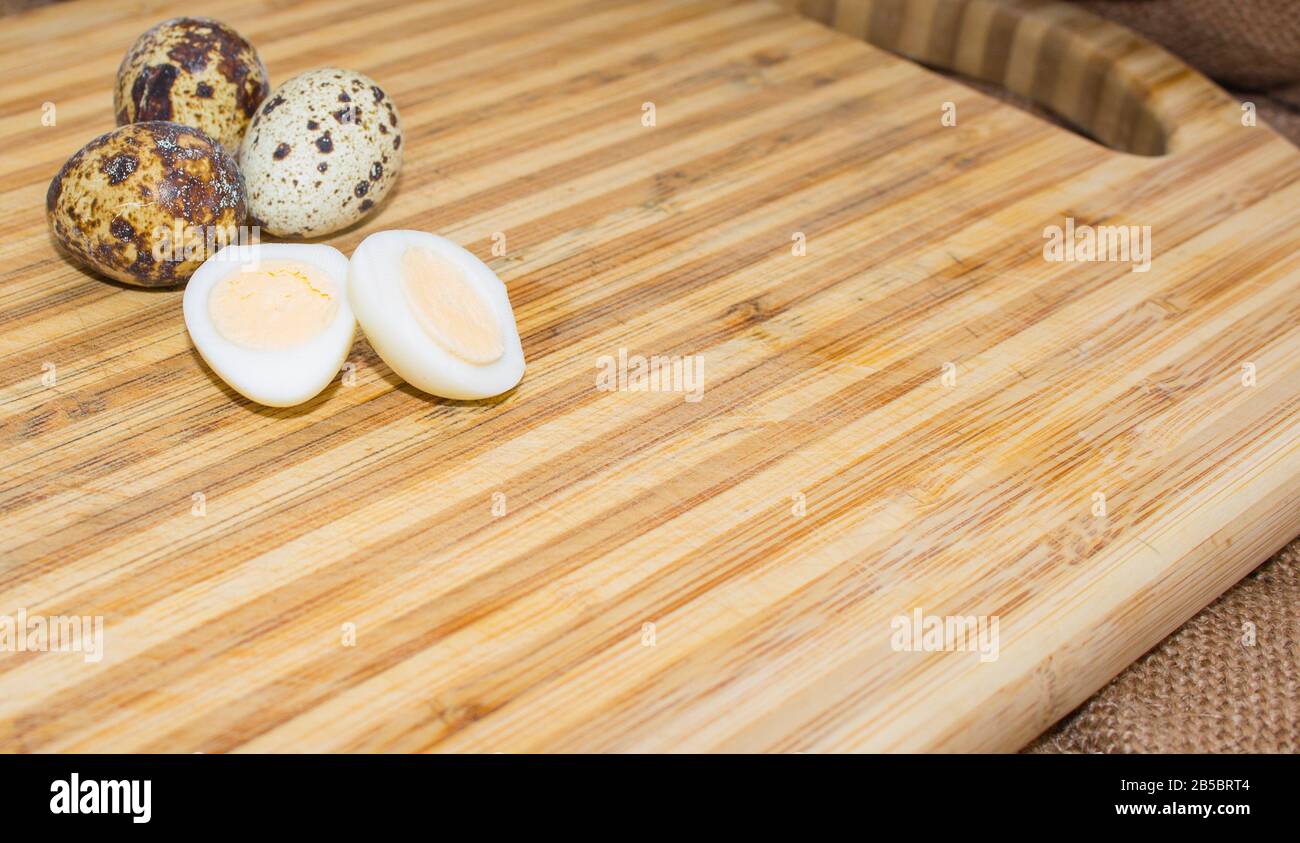 Hard boiled quail egg halves with egg shells on wooden board, photographed with natural light Stock Photo