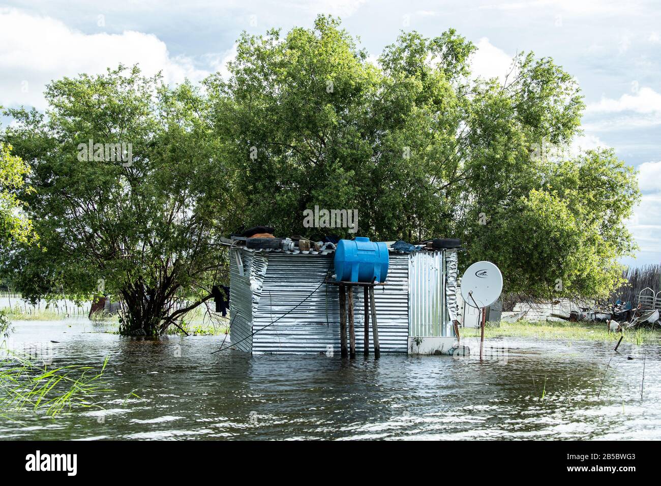 Flooded corrugated iron shack, complete with water tank and satellite dish,  when the Okavango River burst its banks. Stock Photo