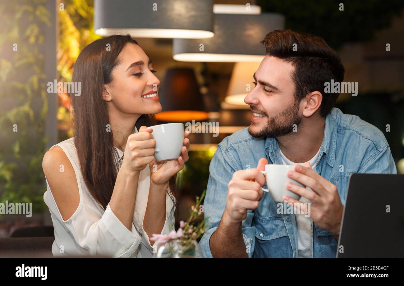 Young couple tasting coffee enjoying flirt and conversation in cafe Stock Photo