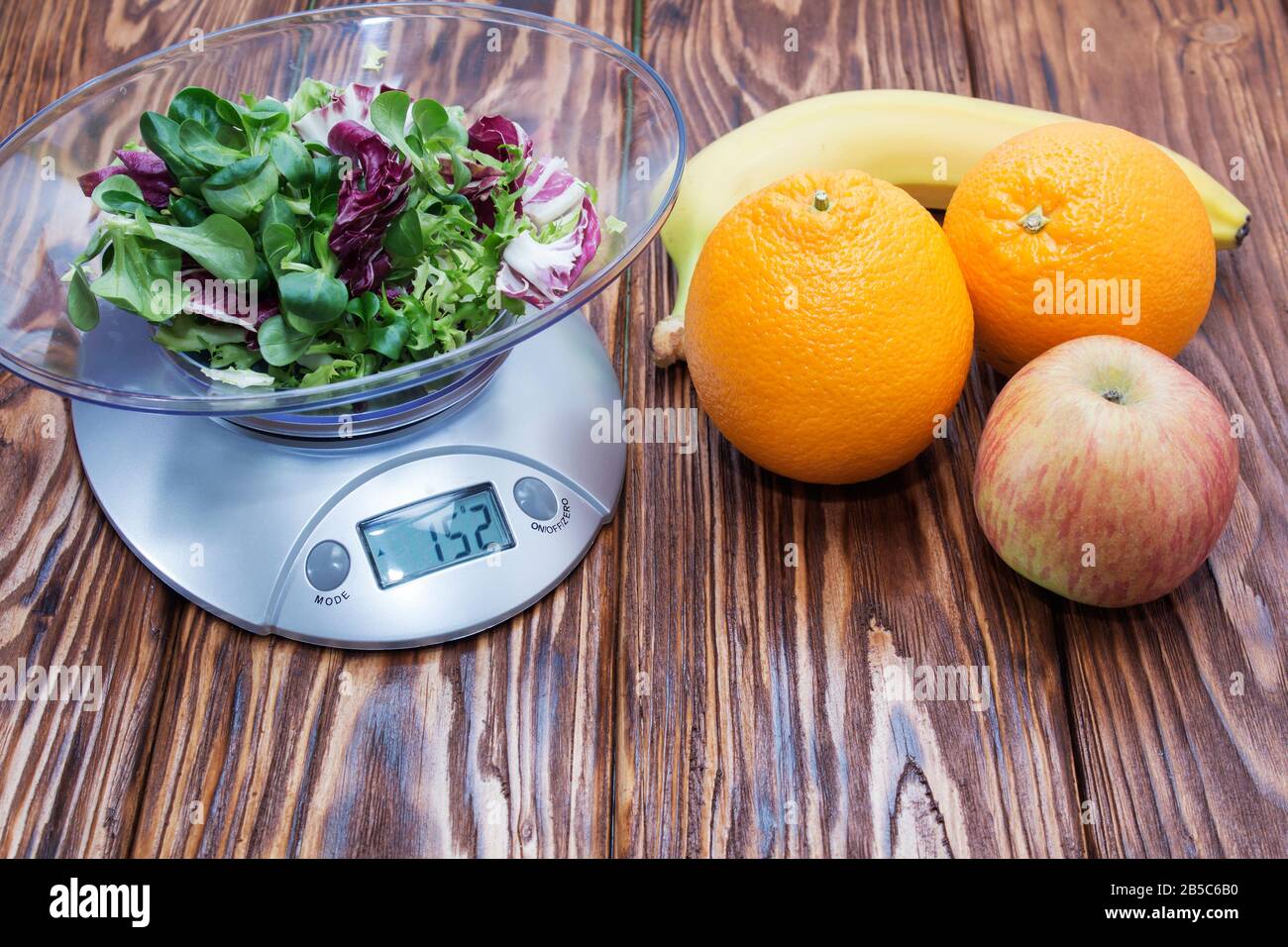 green lettuce leaves on the kitchen scale. banana Apple orange on wooden table Stock Photo