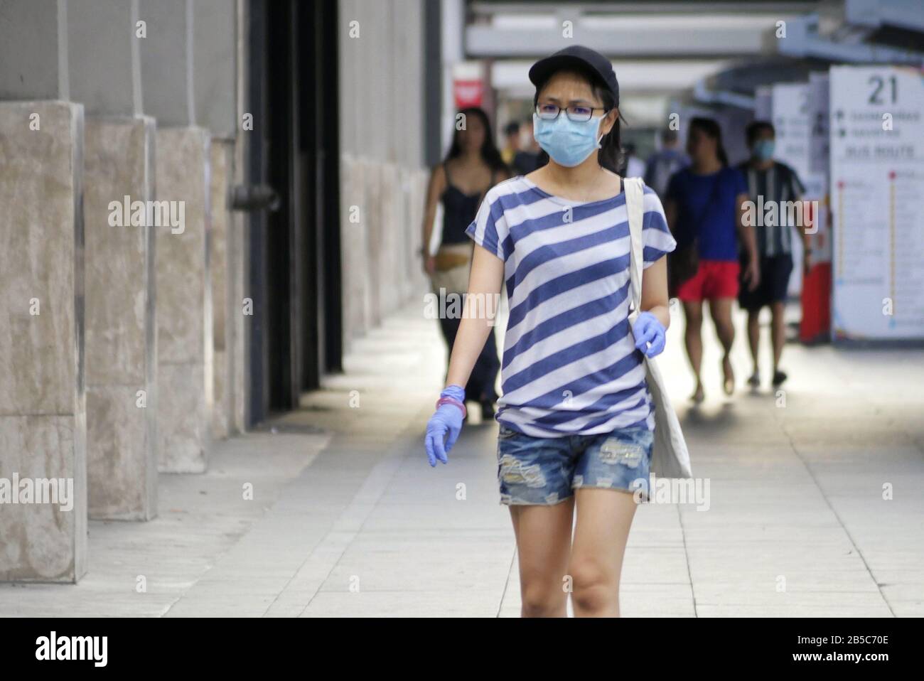 Makati City, National Capital Region, Philippines. 8th Mar, 2020. A woman wears a face surgical mask and gloves due to the Corona Virus scare and outbreak. Credit: George Buid/ZUMA Wire/Alamy Live News Stock Photo
