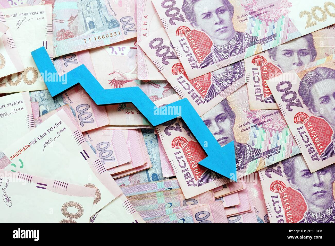 Ukrainian cash hryvnia and down arrow. The economic crisis and inflation. Stock Photo