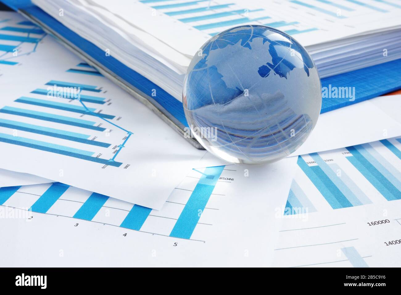 Global business concept. Glass globe and financial charts. Stock Photo