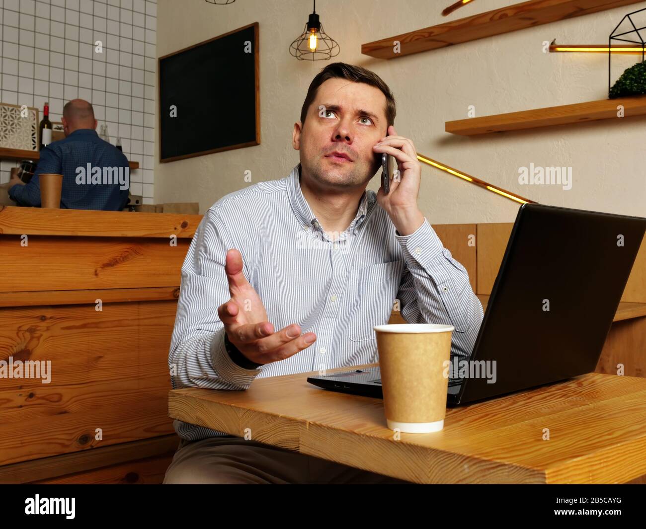 Confused and surprised man speaking on the phone in a cafe. Stock Photo