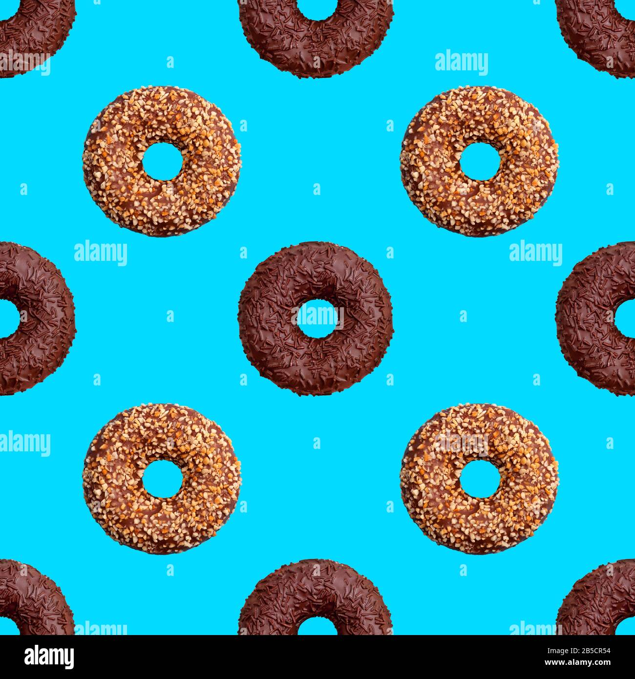 Seamless pattern of chocolate and nut donuts on blue background isolated top view, colorful donut repeating ornament, bagels wallpaper, sweet cakes Stock Photo