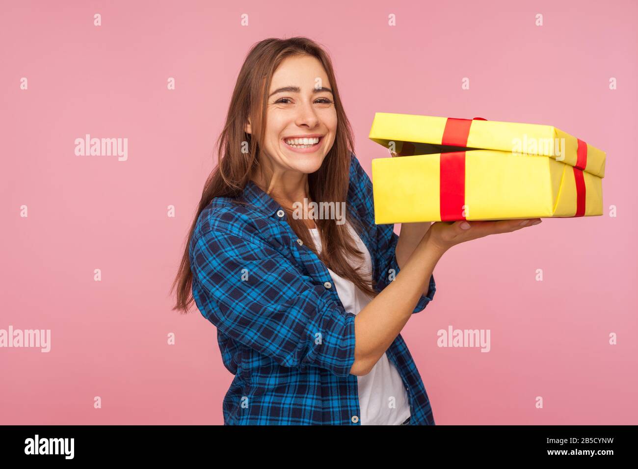 Nice holiday present, bonus! Portrait of happy beautiful girl in checkered shirt holding unwrapped box and looking at camera with toothy smile, excite Stock Photo