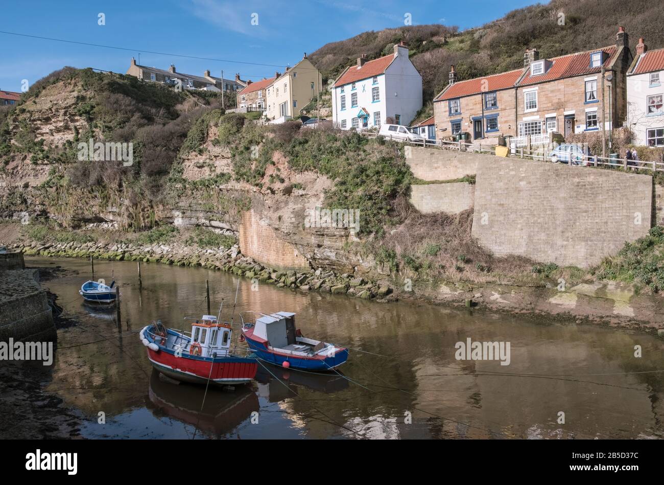 Traditional fishing village harbour with sailing boats at high tide, Staithes, North Yorkshire coast, England, UK Stock Photo