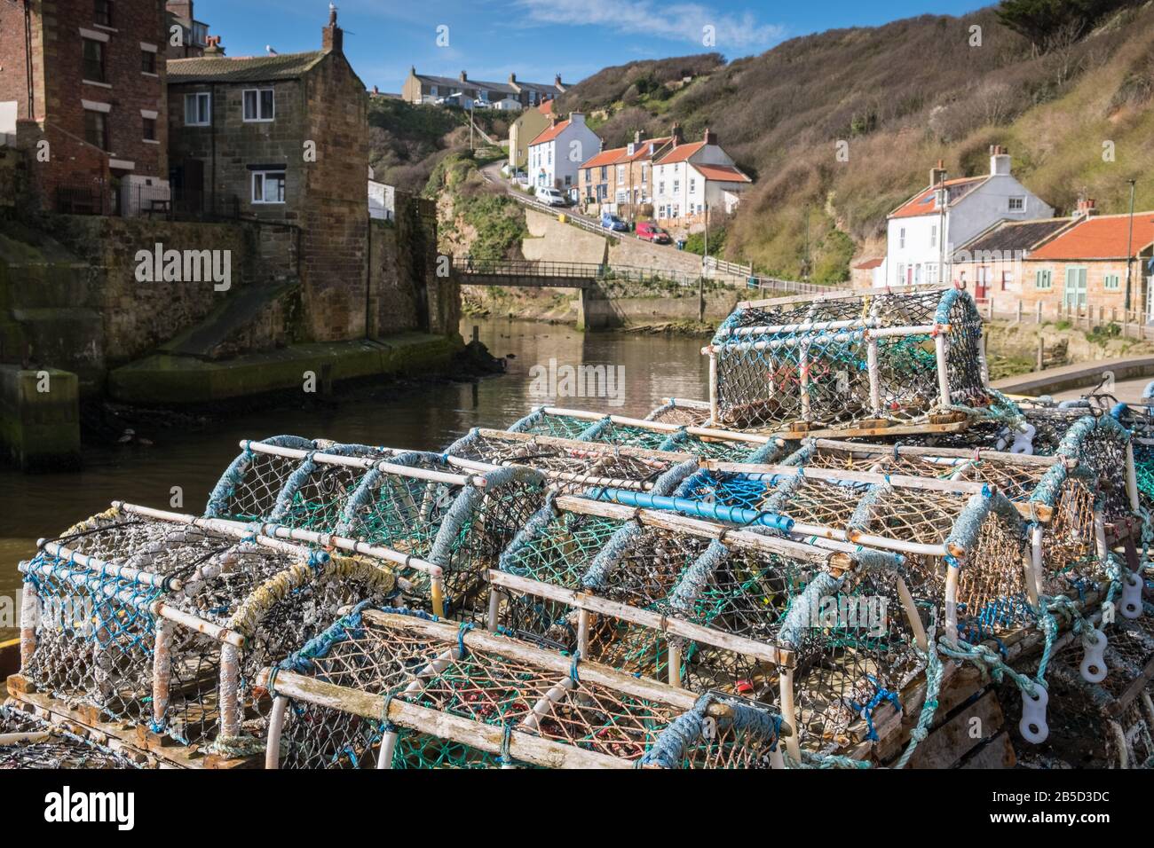 Staithes, North Yorkshire, UK, a traditional fishing village coastal harbour scene, with fishing pots in the foreground. Stock Photo