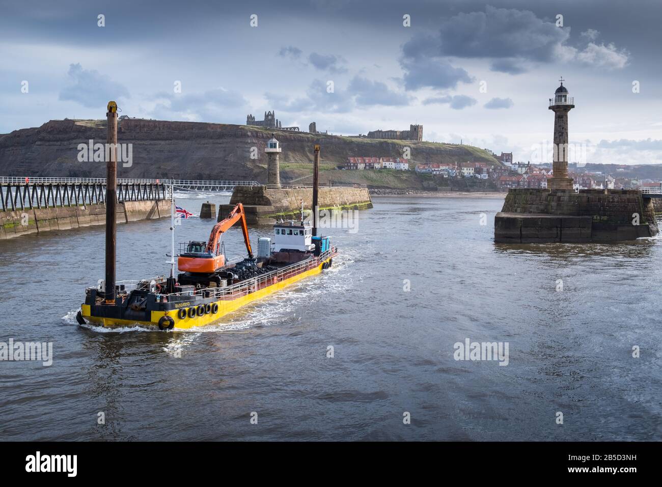 The Sandsend dredging boat leaves Whitby taking refuse from the harbour bed out to sea, North Yorkshire, England, UK Stock Photo