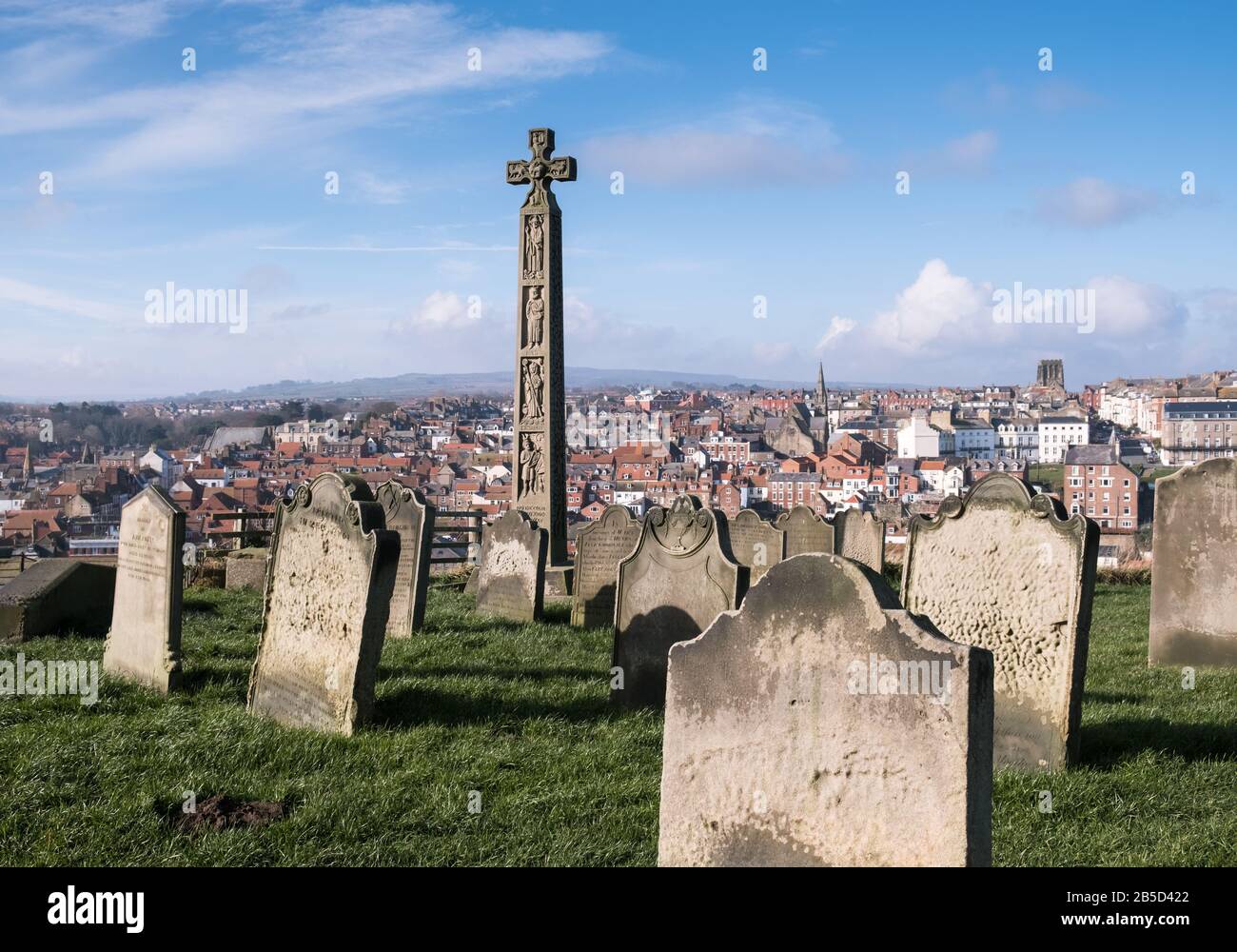 View across St Mary's churchyard towards the coastal town of Whitby, featuring the Caedmon Cross, North Yorkshire coast, England, UK Stock Photo