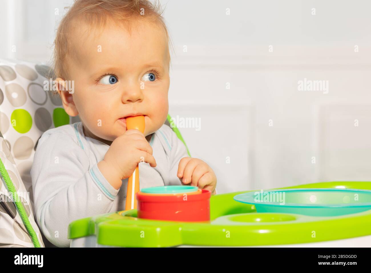 Close portrait of toddler baby boy sit in high chair holding plastic