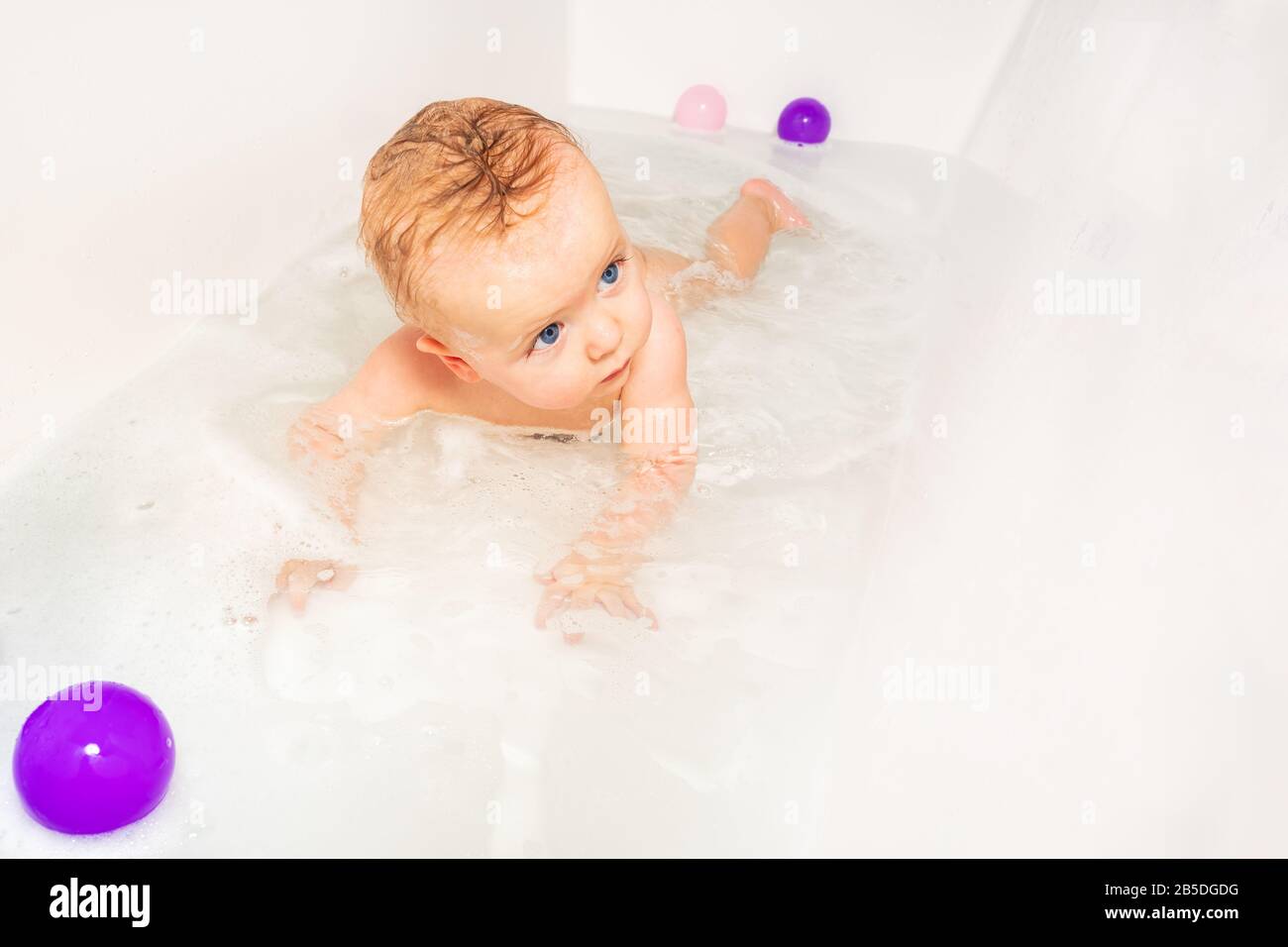 Little Cute Infant Baby Play In Water Of Bath Tub On The Belly With Toys And Soap Stock Photo Alamy