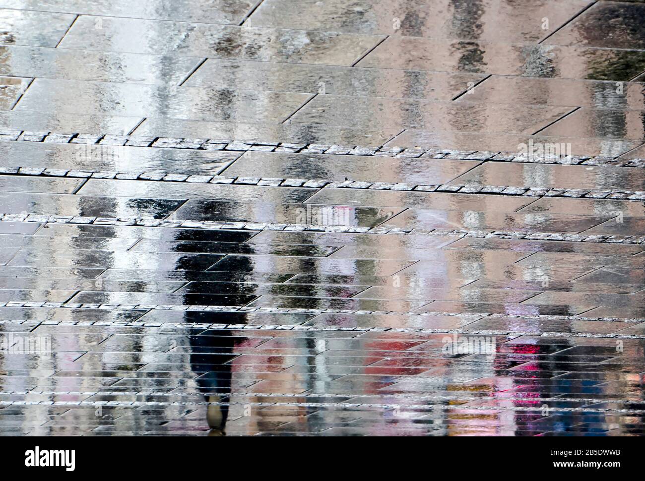 Abstract blurry background of reflection shadow silhouette in a puddle, of people walking alone city street in the rain Stock Photo