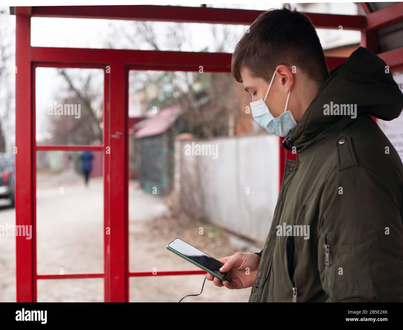 guy in a medical mask stands at a bus stop. isolated to avoid viral disease covid-19 measles flu chickenpox cold. Stock Photo