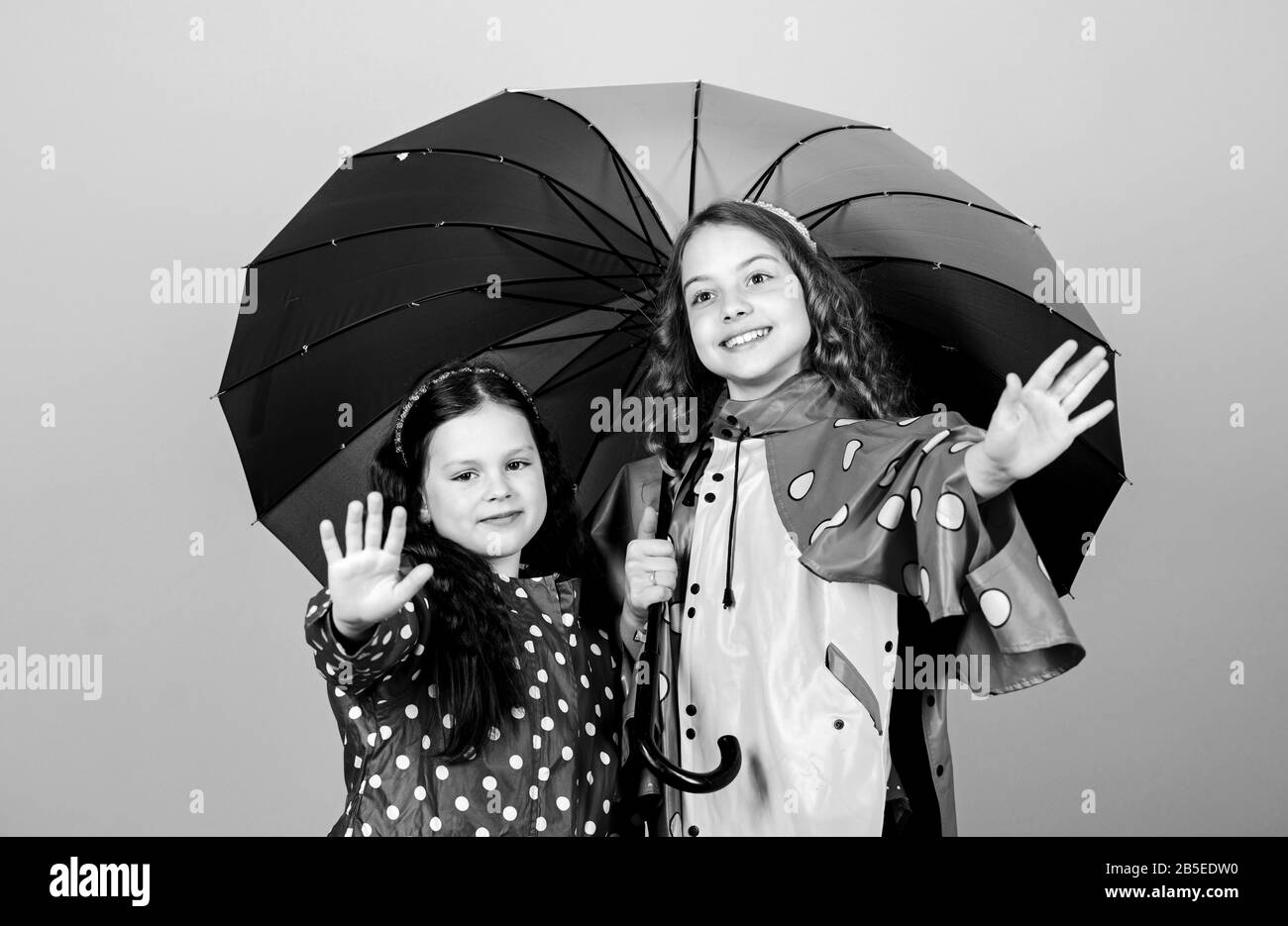 happy little girls with colorful umbrella. autumn fashion. cheerful hipster children, sisterhood. rain protection. Rainbow. family bonds. Little girls in raincoat. Fresh air and good mood. Stock Photo