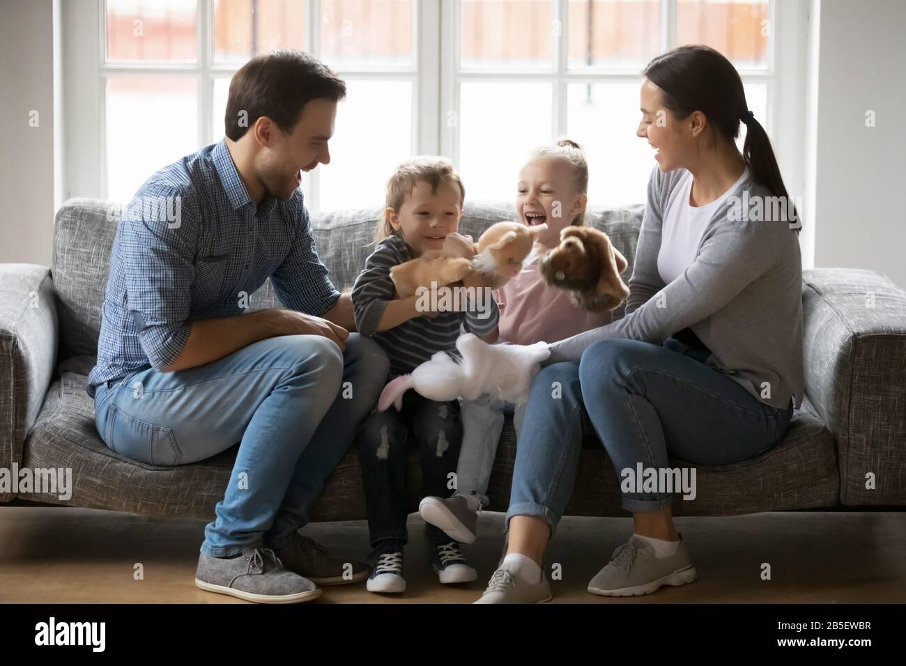 Happy parents wearing hand toys, playing with kids Stock Photo - Alamy