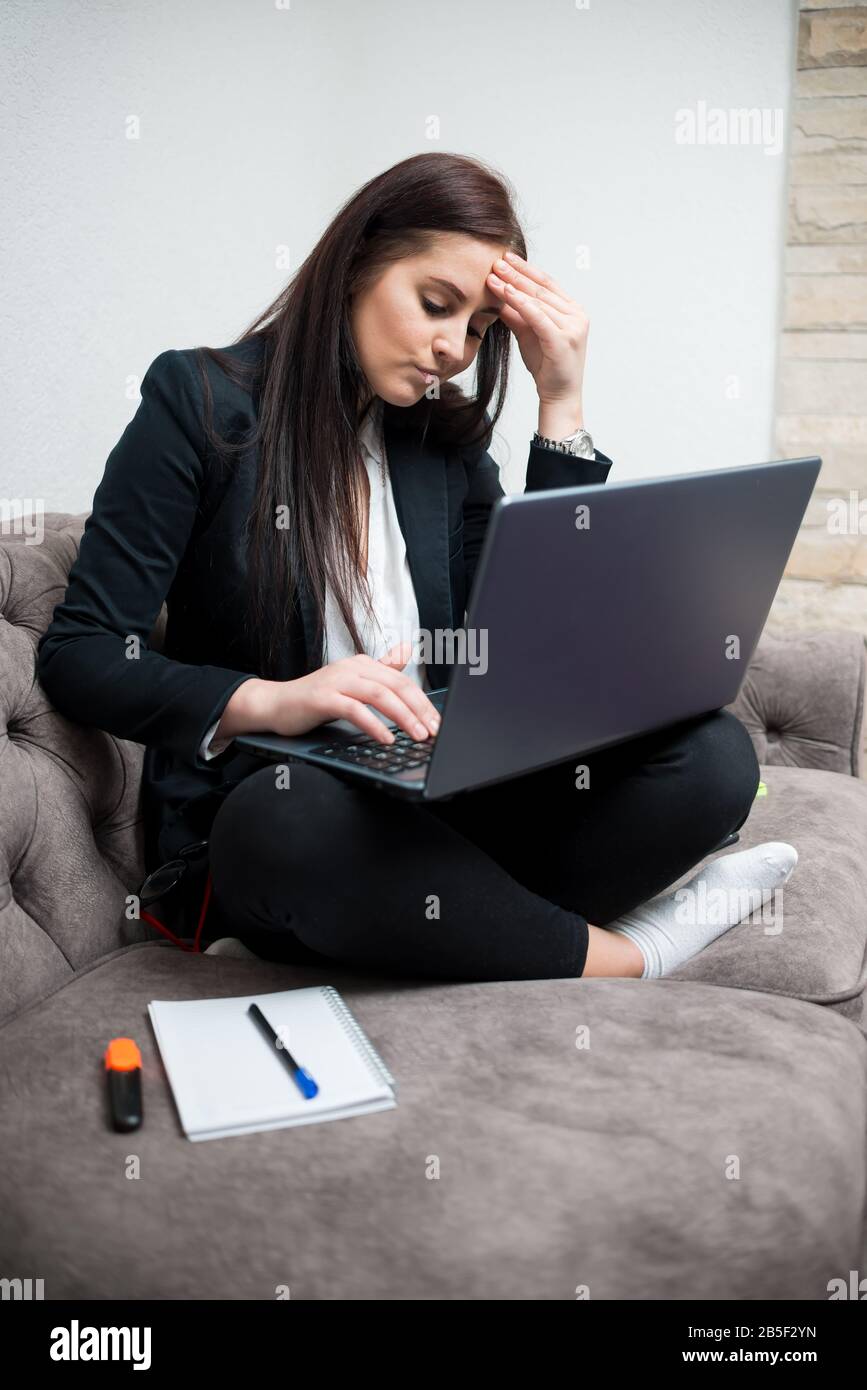 Woman freelancer worried looking at laptop and holding head Stock Photo