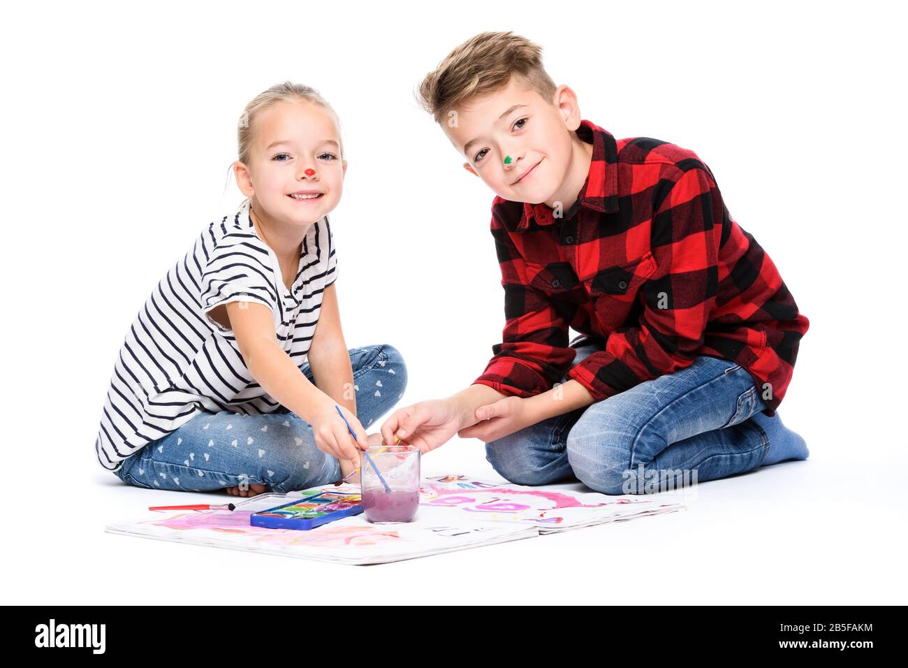 Brother and sister having fun painting with watercolors. Happy creative children at art class. Art therapy concept on white background. Stock Photo