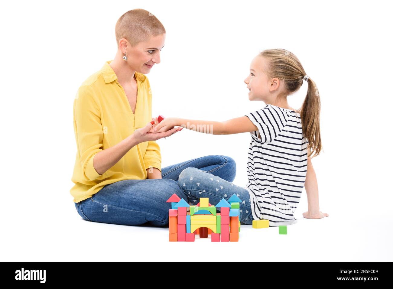 Young girl in child occupational therapy session doing sensory playful exercises with her therapist. Child therapy concept on white background. Stock Photo