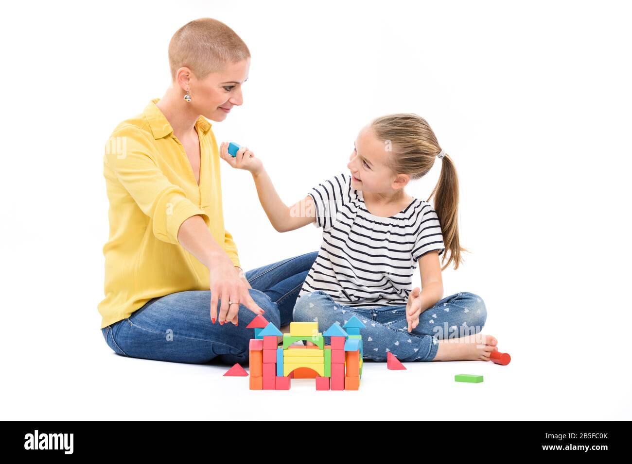 Young girl in child occupational therapy session doing sensory playful exercises with her therapist. Child therapy concept on white background. Stock Photo