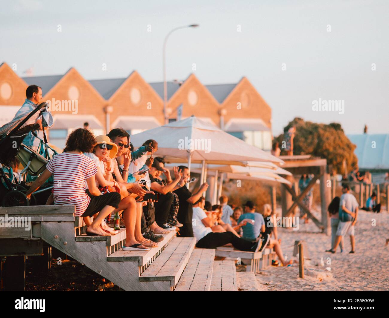 Some Australian locals sitting on some steps adjacent to the beach in Australia Stock Photo