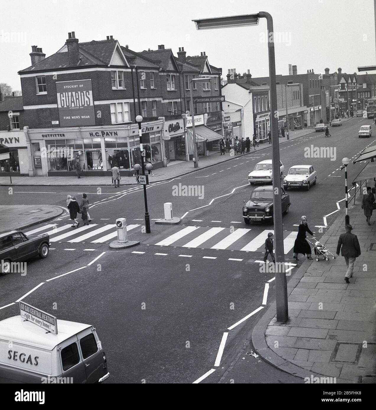 Aerial view of a new road safety measure, a zebra or pedestrian crossing on a busy south london high street, circa late 1960s. First introduced in the UK in 1949, a level crossing gives priority to pedestrians and were put in places where there were shops, schools and other amenities used by pedestrians. Motorists have to give way.  Motorcars of the era can be seen, with a Segas van on the left. Stock Photo