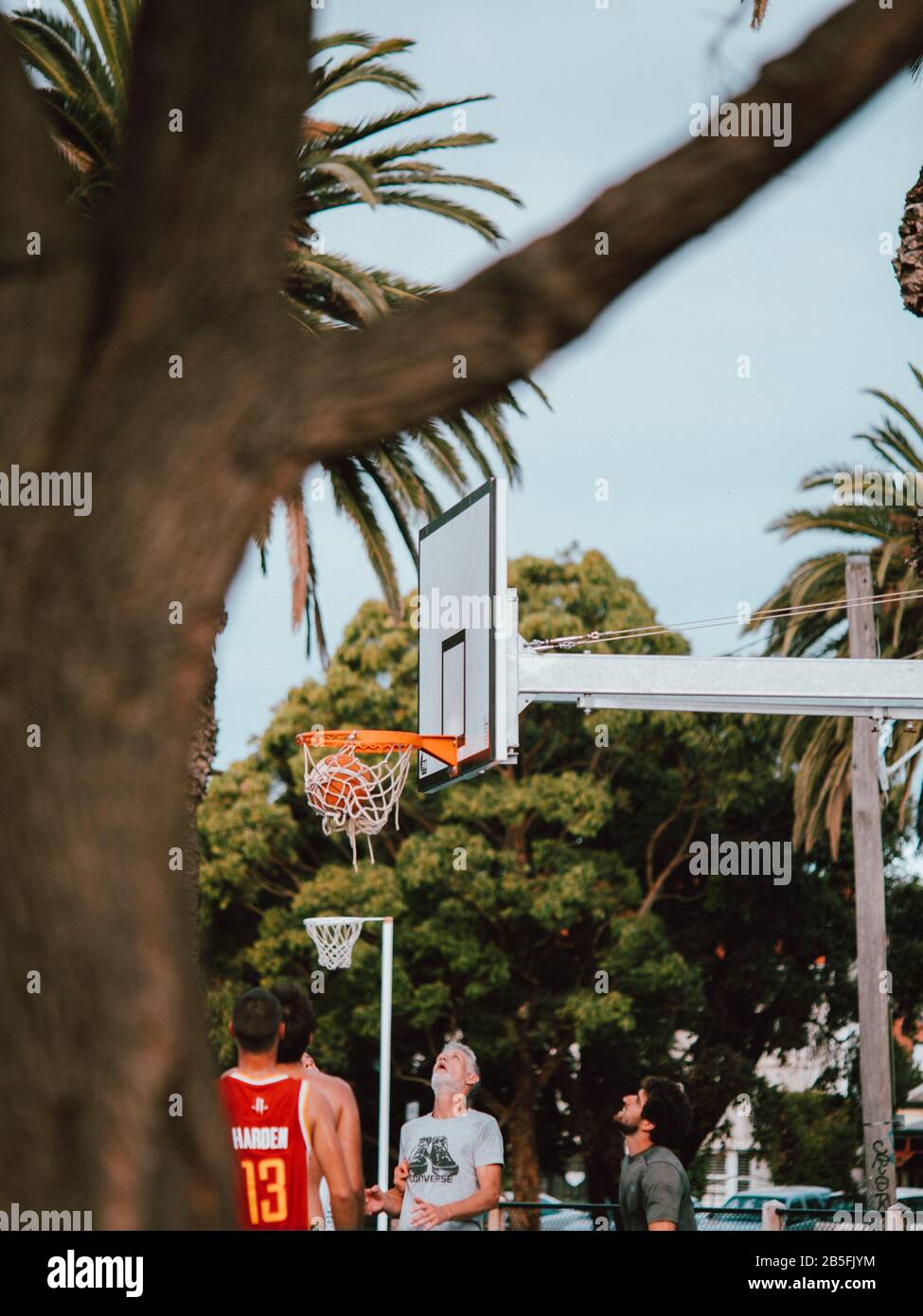 Some Australian locals playing a game of basketball, surrounded by palm