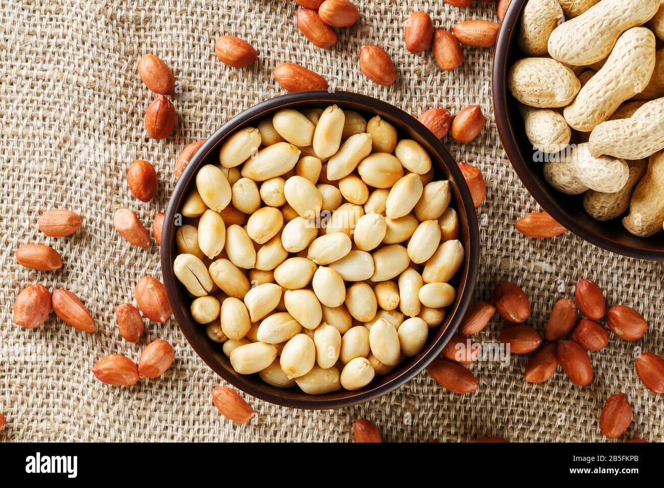 Peanuts in the shell and peeled closeup in a cup. Background with ...