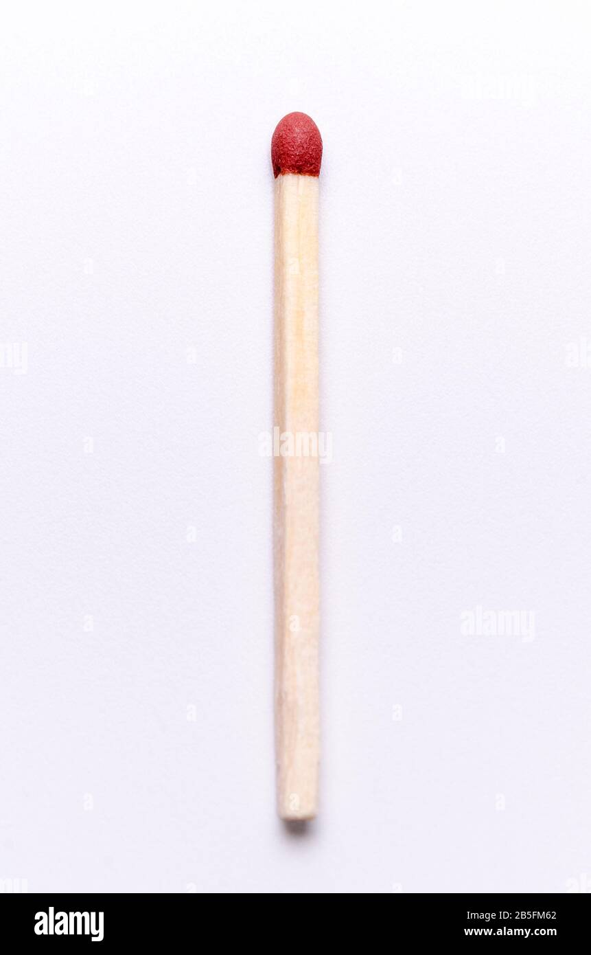 One single matchstick, close up macro of red matchstick head against white background Stock Photo