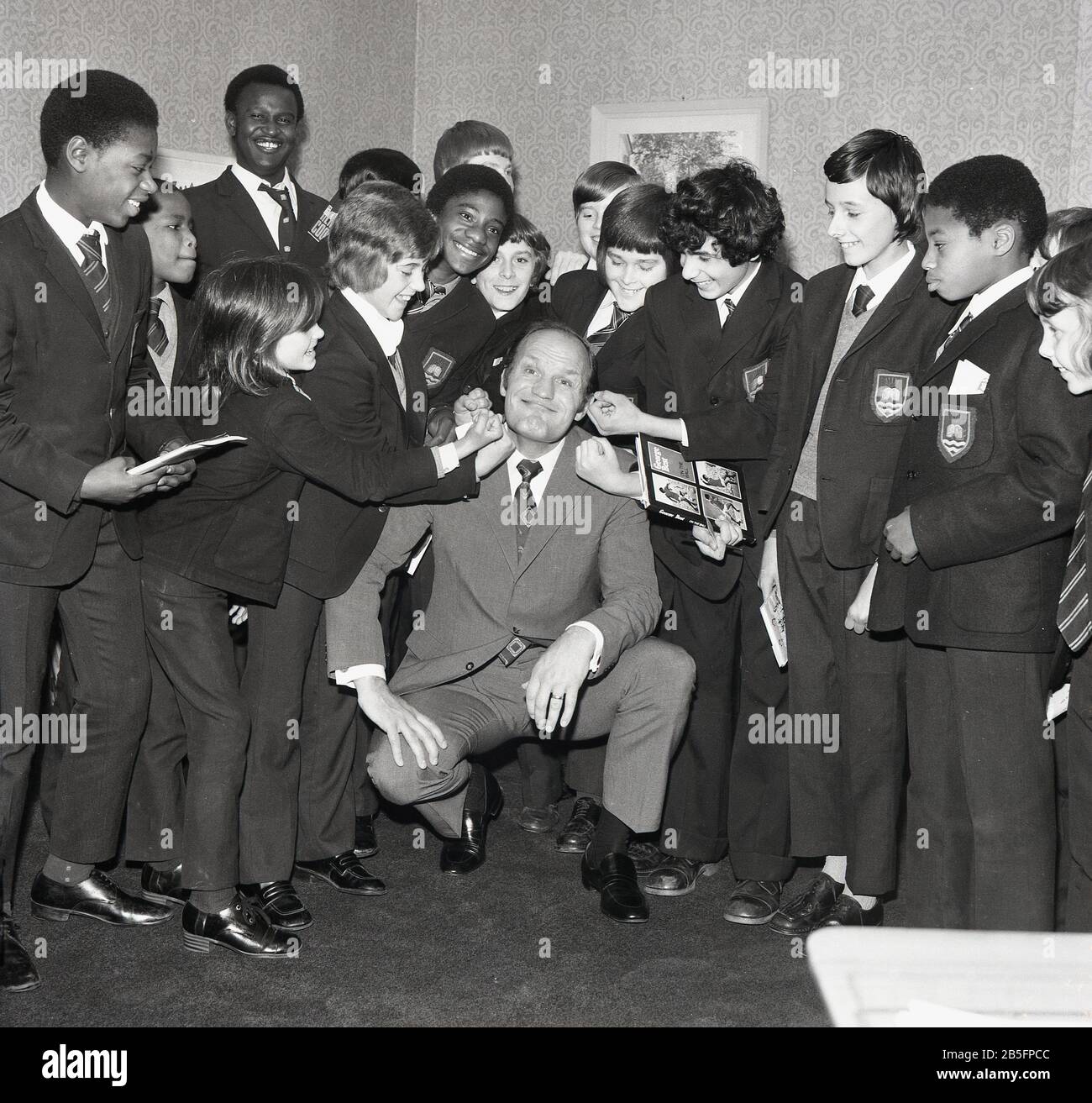 1972, historical, 'take it on the chin'....British boxing legend Henry Cooper having fun with a group of South London schoolboys on a visit to an inner city secondary school. Stock Photo