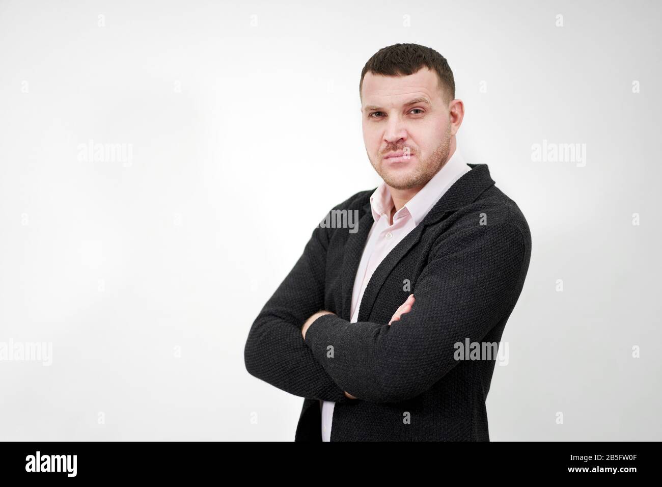 Portrait of an elegant young businessman standing with arms crossed ...