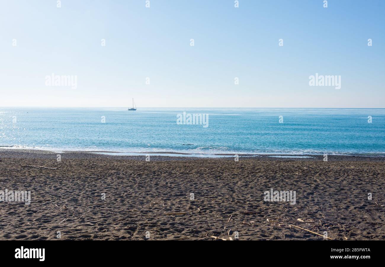 Winter seaside scene in Tuscany with boat far at sea, a sandy beach, sunny weather and calm sea Stock Photo