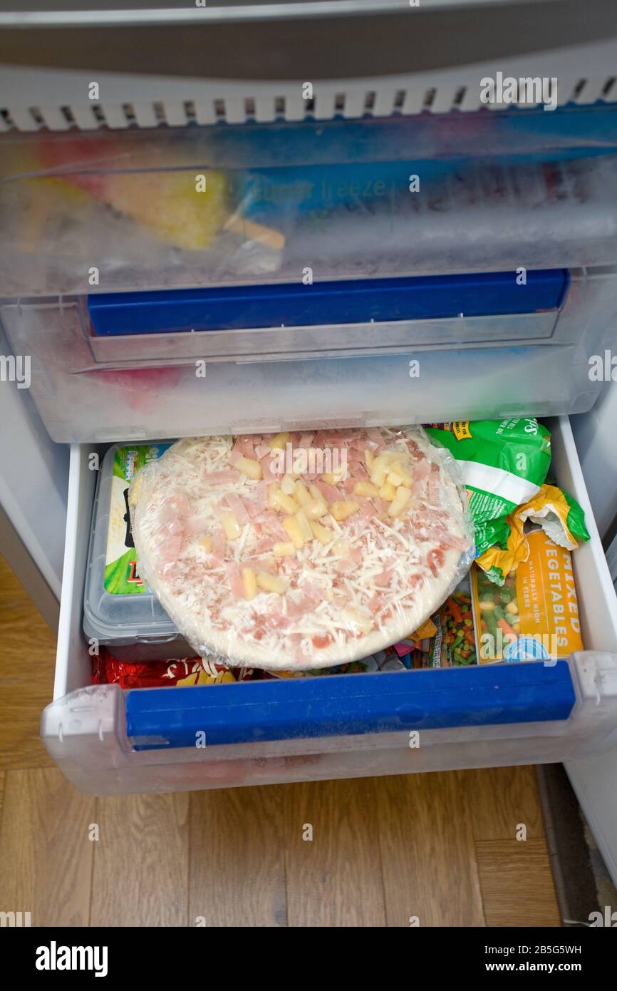 Frozen pizza in open drawer of fridge freezer Stock Photo