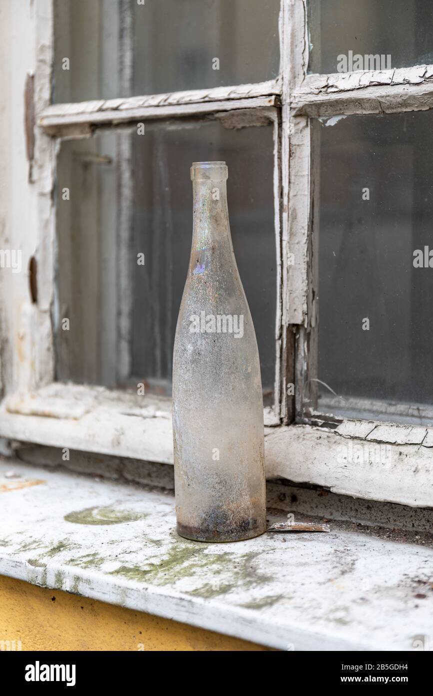 Dirty old bottle on a dirty window ledge Stock Photo