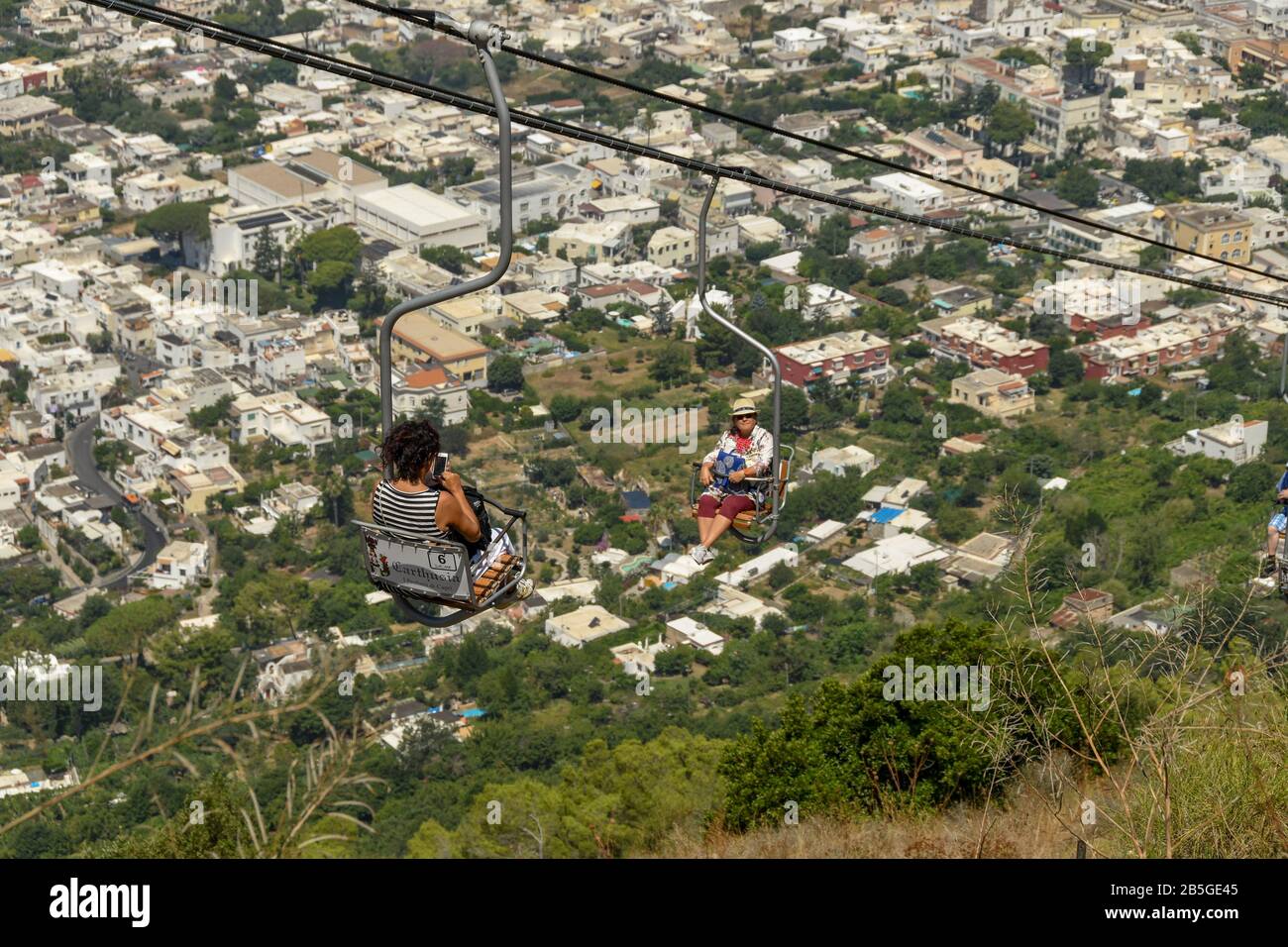 ANACAPRI, ISLE OF CAPRI, ITALY - AUGUST 2019: People on a chair lift travelling up and down the mountain to the summit of Mount Solaro above Anacapri Stock Photo