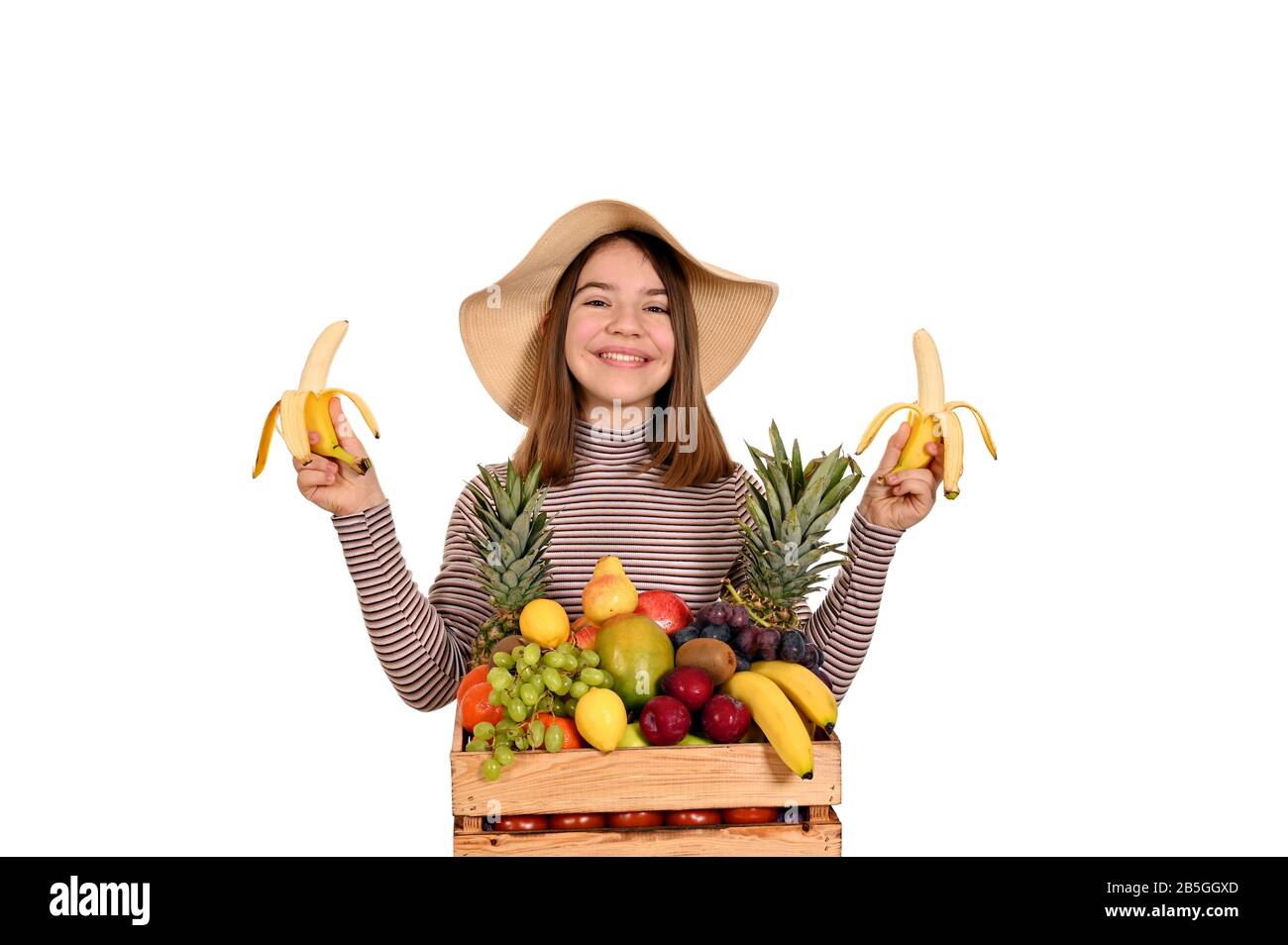 happy girl holds bananas and  wooden crate with fruit Stock Photo