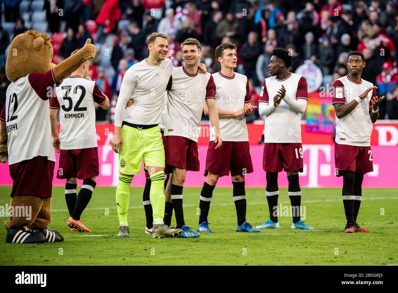 08 March 2020, Bavaria, Munich: Football: Bundesliga, Bayern Munich - FC Augsburg, 25th matchday in the Allianz Arena. Mascot Berni (l-r), goalkeeper Manuel Neuer, Thomas Müller, Benjamin Pavard, Alphonso Davies and David Alaba from FC Bayern Munich celebrate their victory with the fans. Photo: Matthias Balk/dpa - IMPORTANT NOTE: In accordance with the regulations of the DFL Deutsche Fußball Liga and the DFB Deutscher Fußball-Bund, it is prohibited to exploit or have exploited in the stadium and/or from the game taken photographs in the form of sequence images and/or video-like photo series. Stock Photo