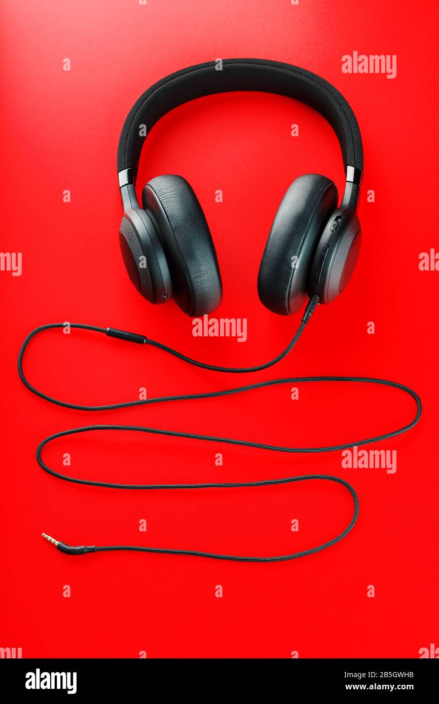 Wireless black headphones on a red background. View from above. In-ear  headphones for playing games and listening to music tracks. Modern style  Stock Photo - Alamy