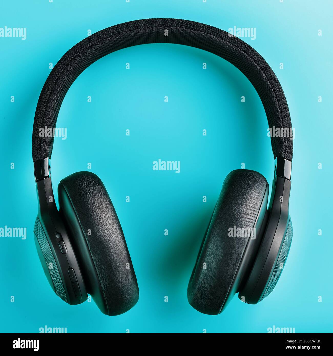 Black wireless headphones on a blue background. Overhead, isolated professionalgrade headphones