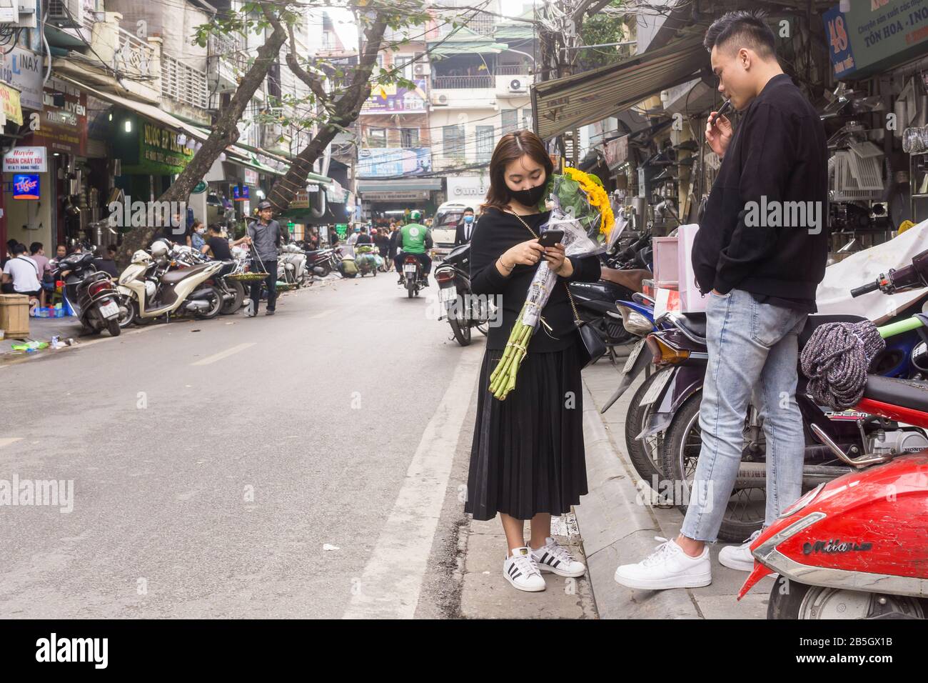Hanoi street scene - Two Vietnamese people in their 20s chatting on the street of the Old Quarter in Hanoi, Vietnam, Southeast Asia. Stock Photo